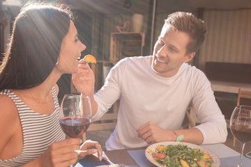 Caring man. Caring beaming man wearing plain white shirt giving healthy tasty fruits his girlfriend