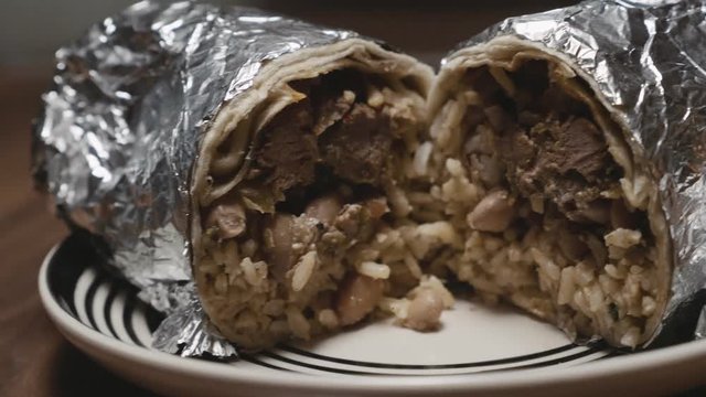 Slow motion video of a burrito cut in half with salsas and guacamole from chipotle close up