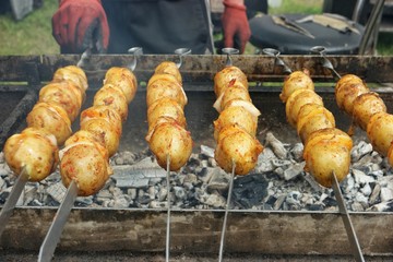 Potatoes with bacon on skewers are baked on the grill. Festival of Ukrainian national cuisine in the open air.Ivano-Frankivsk, Ukraine