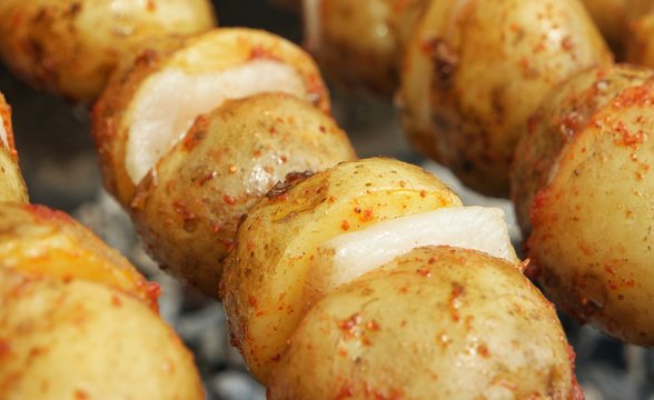 Potatoes with bacon on skewers are baked on the grill. Festival of Ukrainian national cuisine in the open air.Ivano-Frankivsk, Ukraine