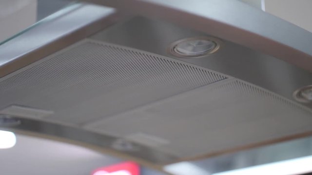 Close up of a modern kitchen hood fan in silver chrome above an oven.