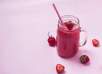 Strawberry smoothie in a glass jar on the pink background