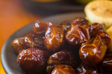 dried dates and figs in a ceramic plate on a wooden table