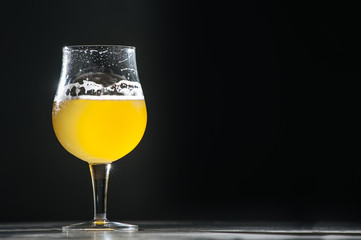 Glass beer with foam on black background with copyspace