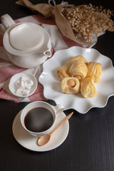 Tasty mini sausage in bread rolls and Cup of hot coffee on dark background