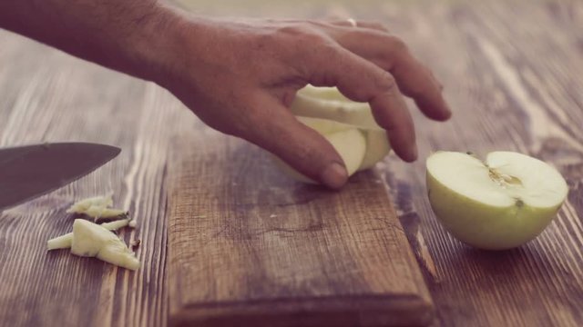 Man's hands cutting the apple on wooden board