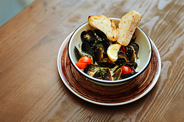 Mussels and bread. Nice delicious mussels in creamy sauce lying near toasted bread with lemon and cherry tomatoes