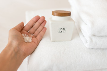 Woman's  hand holding  bath sea salt on the white towel