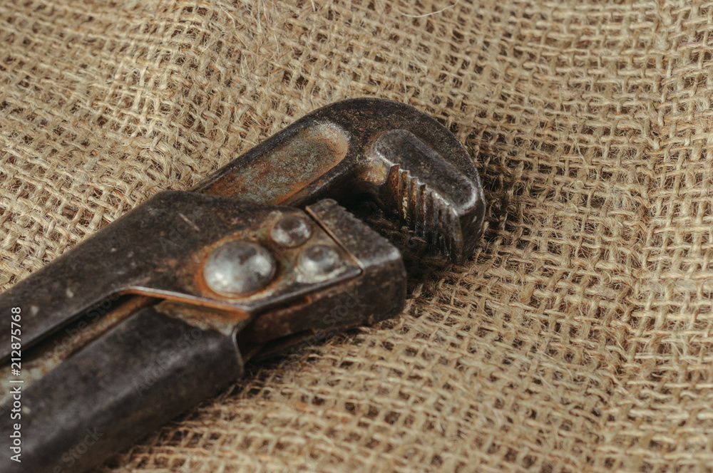 Wall mural old adjustable wrench on a natural fabric background.