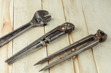 Two old adjustable wrench and other tools on a natural  wooden background.