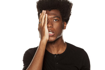 Portrait of young worried african american modern man slapped himself in the face on white background