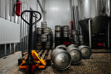 Many metal beer keg stand in a warehouse of brewery. Time to delivery. Beer kegs on the production...