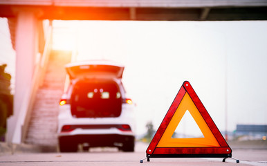 Red triangle warning sign on the road,car with breakdown alongside the road.