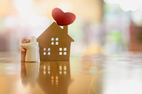 Ceramic couple dolls hugging on the floor with blur heart and home model background.
