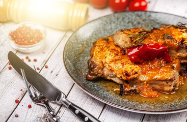 Mexican cuisine, pork or beef steak with a spicy sauce of salsa. with red pepper, marasm and titanium, cherry tomatoes, knife and fork.