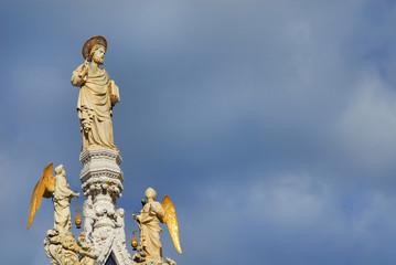 Saint Mark blessing medieval statue with angels at the top of Venice Cathedral, 15th century (with clouds and copy space)