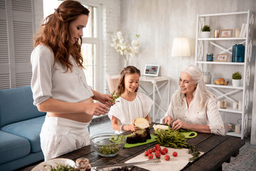 Salad with arugula. Expecting caring woman holding arugula while cooking healthy salad for her family