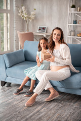 Obraz premium Caring daughter. Happy beaming pregnant woman feeling amazing while receiving present from caring daughter