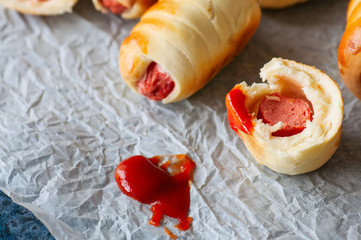 Pigs in a blanket on a baking paper. Close up. Fast food, beer snack or lunch box food concept.