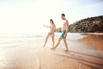 Fototapeta premium lovers run along the beach / guy and girl run along the summer sea beach, rest on the sea honeymoon