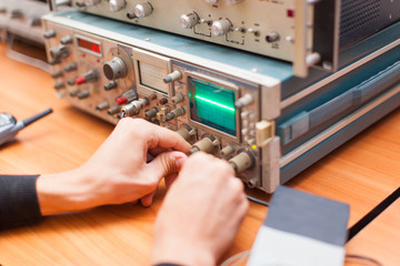 photo man measures the voltage of a tester on an electronic device using a digital oscilloscope
