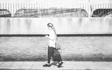 Young woman using smartphone and walking