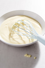Bowl of vanilla custard with blue whisk 