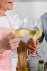cropped shot of elederly couple clinking glasses of wine