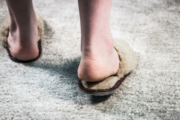 fluffy Slippers on feet on the carpet in the room