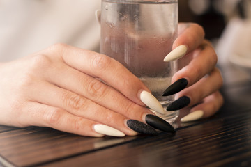 Fototapeta na wymiar Beautiful woman's hands with long polished nails holding glass of cold water