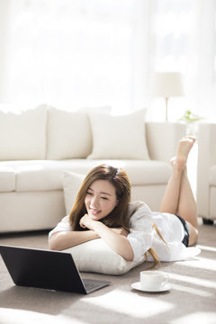 Cheerful young Chinese woman using laptop at home