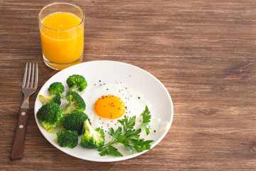 Fried eggs with broccoli and greens. Delicious homemade breakfast. On a wooden table, selective focus