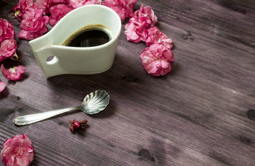 Obraz na płótnie Canvas cup of coffee with pink flowers around on the wooden table