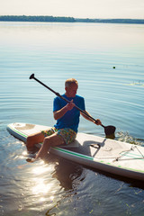 Man is relaxing on a SUP board on a large river