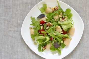 Mixed salad with white beans, greens, cucumbers and sweet peppers, copy space, top view