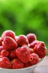 Fresh juicy large strawberry in a bowl close-up outdoors at the cottage