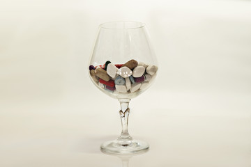 pills in wine glass on white background