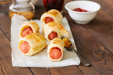 Pigs in a planket. Puff pastry rolls with sausages on a wooden background. Fast food or beer snack concept.