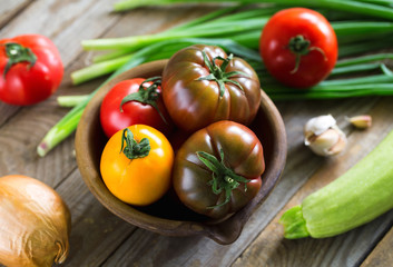 Home-grown various tomatoes and zucchini on vintage wooden boards.