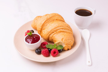 Coffee, fresh croissant with jam and berries for breakfast