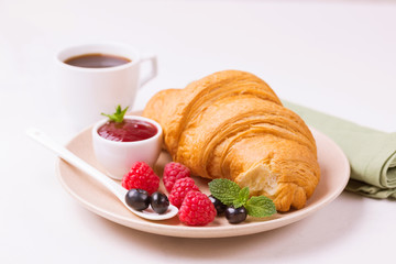 Coffee, fresh croissant with jam and berries for breakfast
