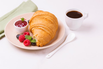 Coffee, fresh croissant with jam and berries for breakfast