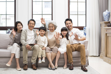 Happy Chinese family waving on sofa