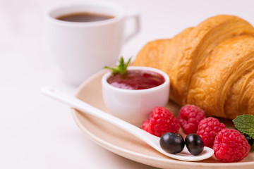 Coffee, fresh croissant with jam and berries for breakfast