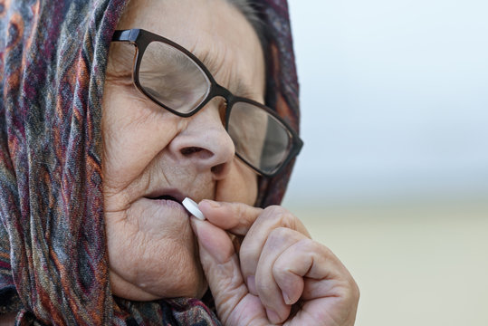 old woman takes pills, close-up, toned
