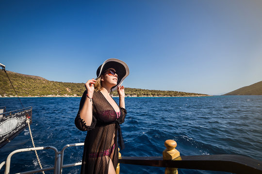 Beautiful girl in hat relaxing on the boat and looking at the island. Travelling vocation tour in Turkey