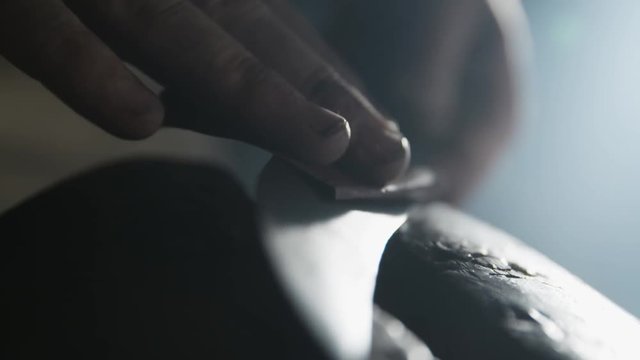 Blacksmith polishing a knife.