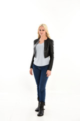 full length portrait of blonde girl wearing casual blue shirt and leather jacket. standing pose, isolated on white studio background.