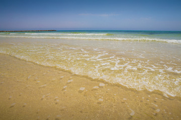 Fototapeta na wymiar Soft blue ocean wave on sandy beach. Bottom. White sand on the beach with turquoise water in Djerba, Tunisia.