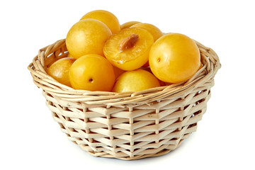 Yellow cherry plums also known as mirabelle plums in woven basket isolated on white background